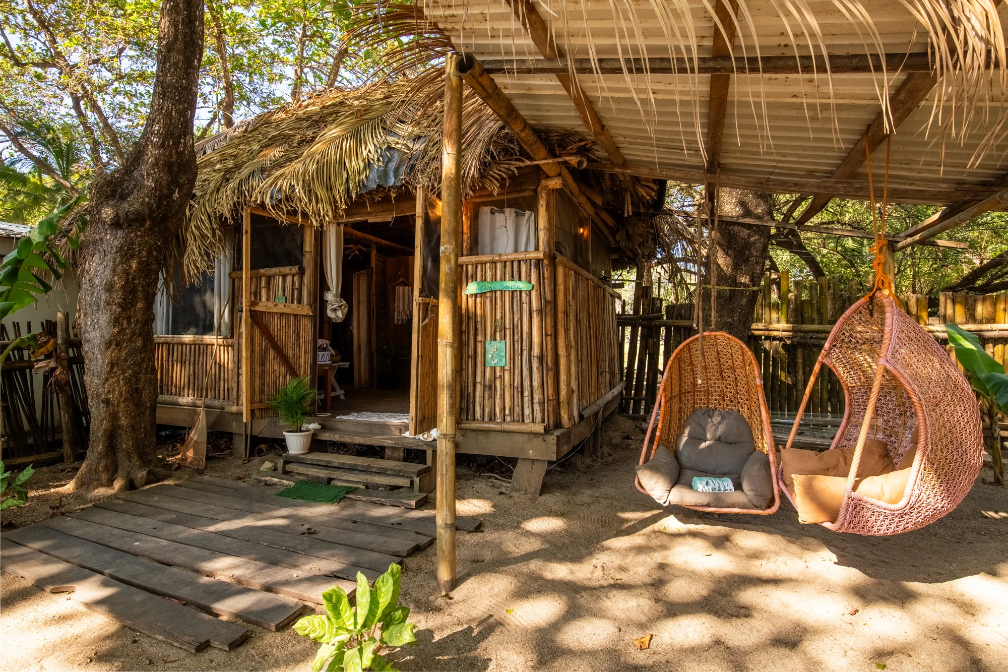 Bamboo Cabina exterior with thatched roof and hanging chairs