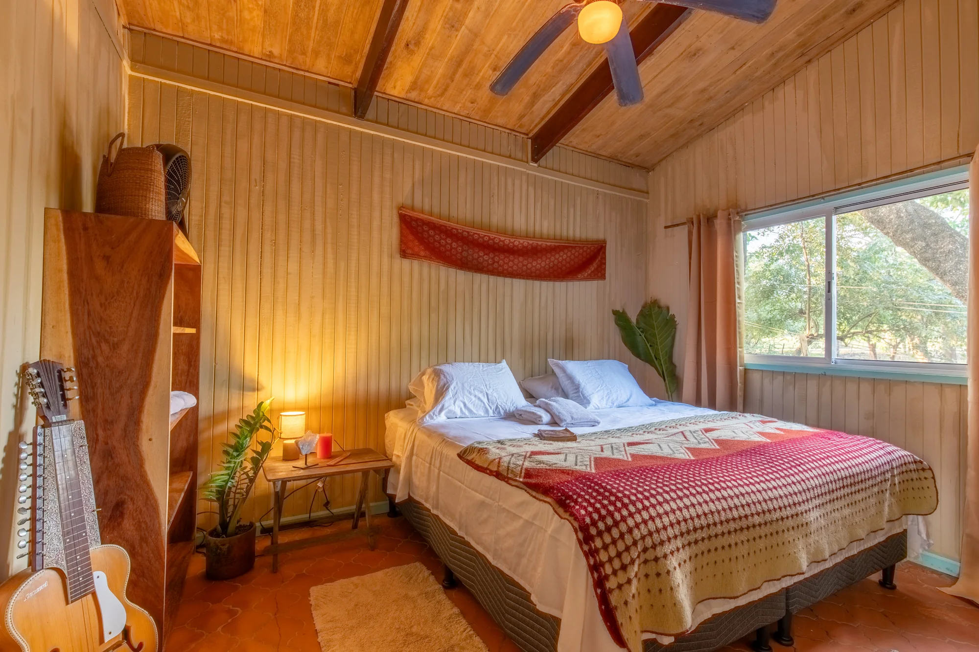 Bedroom with woven blanket, timber ceiling and a guitar