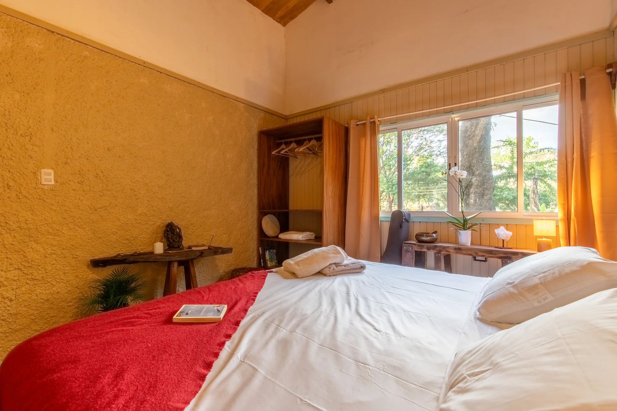 Second bedroom with red bedcover and garden-facing window